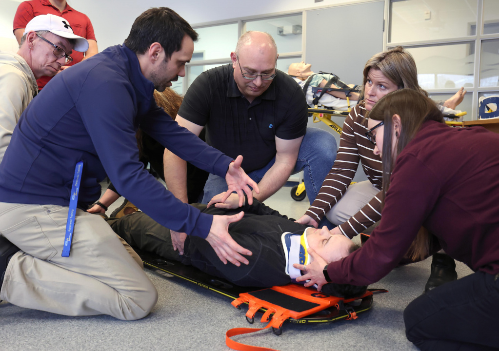 Instructor Mike Miller teaches the learners in the Emergency Medical Responder program how to secure a patient to a spine board