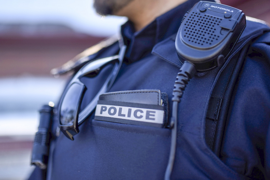 Photo showing the upper torso of a local police officer wearing a protective vest with a two-way radio attached