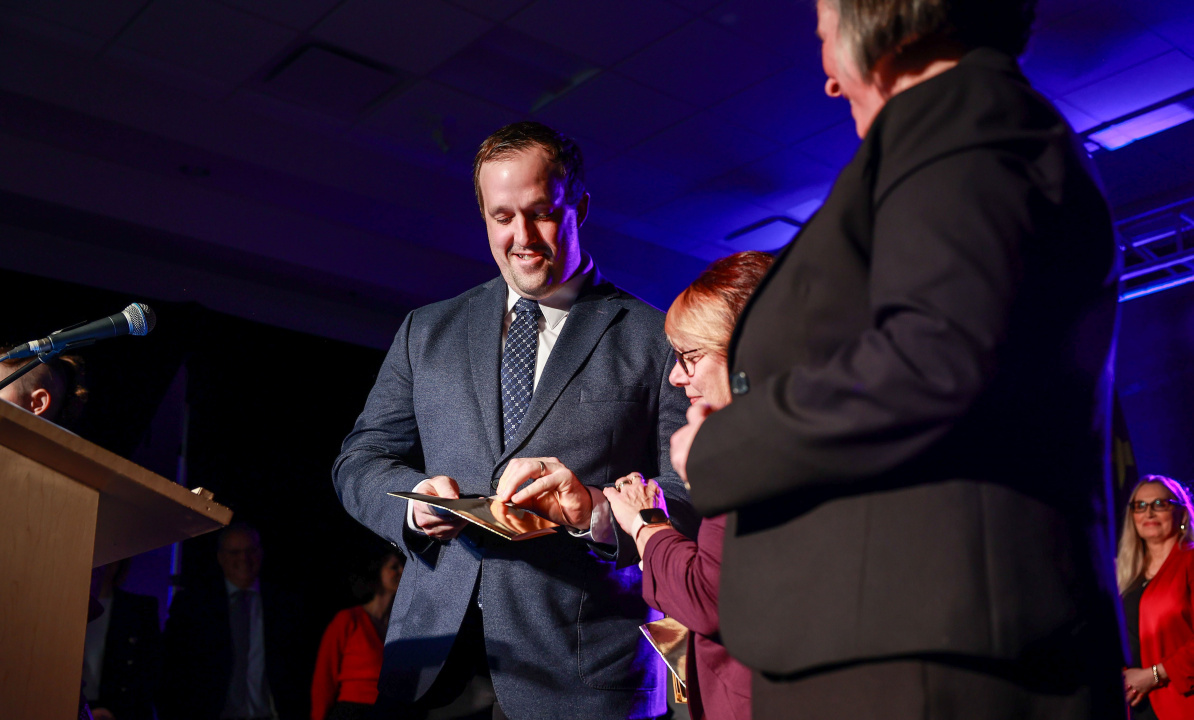 Addictions and Mental Health Minister Brian Comer opens a gold envelope to reveal one of the Integrated Youth Services locations