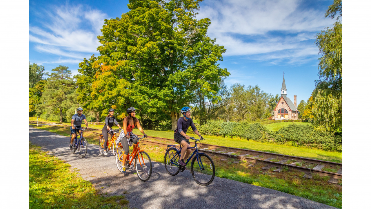 Photo of four people on bicycles on a trail and a church in the background