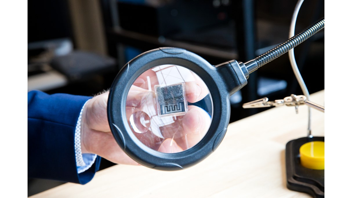 Photo of computer chip held under a magnifying glass