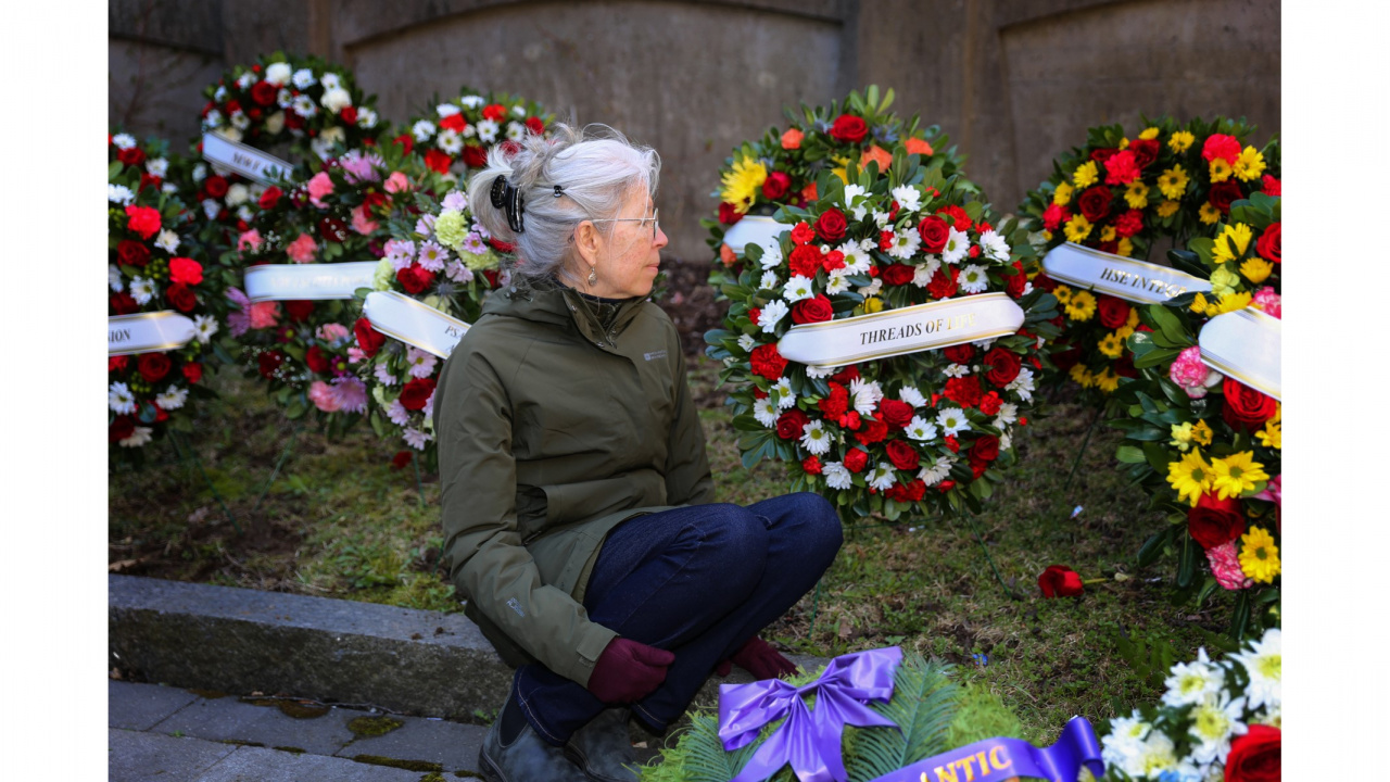 Candace Palumbo of Threads of Life, a support and advocacy organization, sits in front of wreaths placed outside Province House during the 2023 Day of Mourning ceremony. Her husband, Tony, died at age 59 from asbestos-related mesothelioma. (Communications Nova Scotia / File)