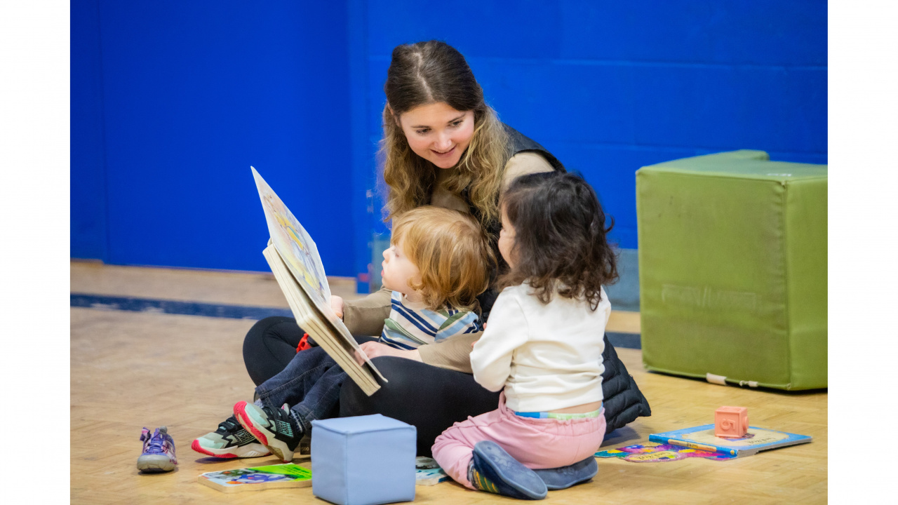 Photo of early childhood educator reading to two children