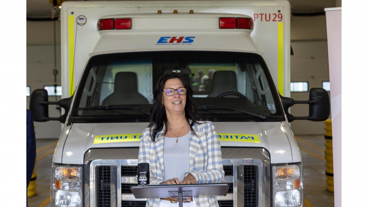 Photo of Health and Wellness Minister Michelle Thompson at a podium in front of an ambulance