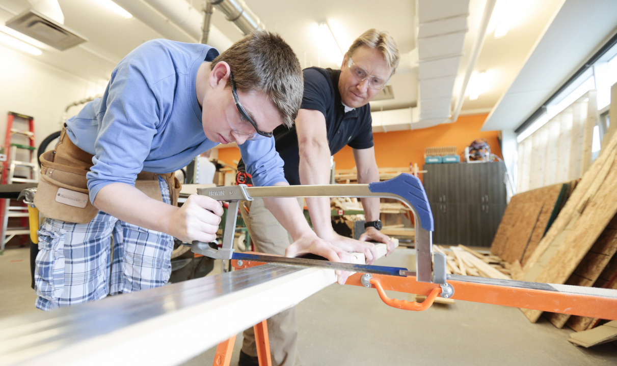 Photo of a student using a hacksaw watched by an instructor
