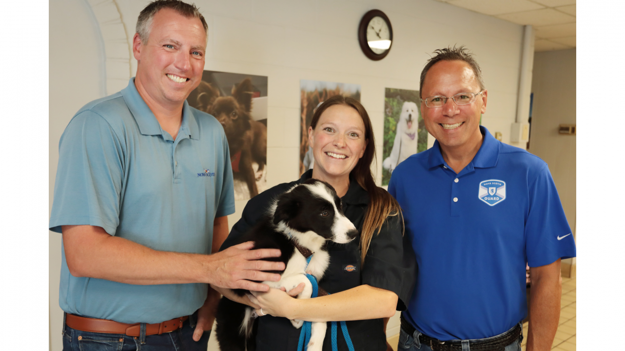 Photo of Agriculture Minister Greg Morrow, Advanced Education Minister Brian Wong and Dr. Laura Wilson, who's holding a border collie