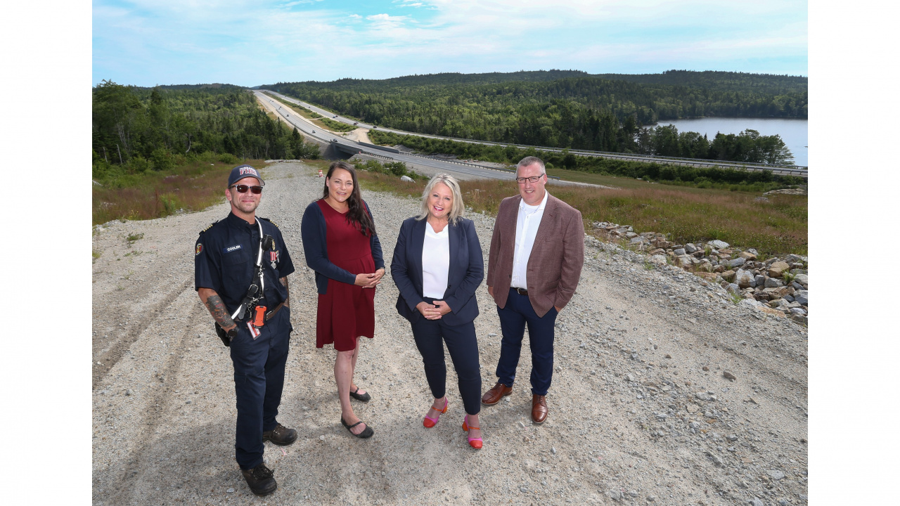 Photo of Public Works Minister Kim Masland and three other people with Highway 103 in the background