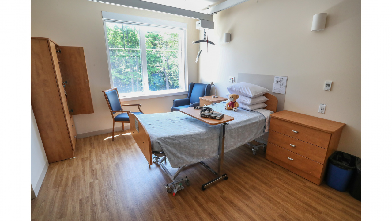 Photo of resident's room at Mahone Bay Nursing Home, including bed, bedside table and chairs