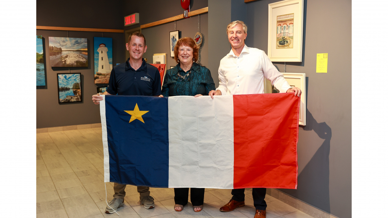 Acadian Affairs and Francophonie Minister Colton LeBlanc, Premier Tim Houston and Diane Racette, President of CSAP, with the Acadian flag during the event. (Communications Nova Scotia)