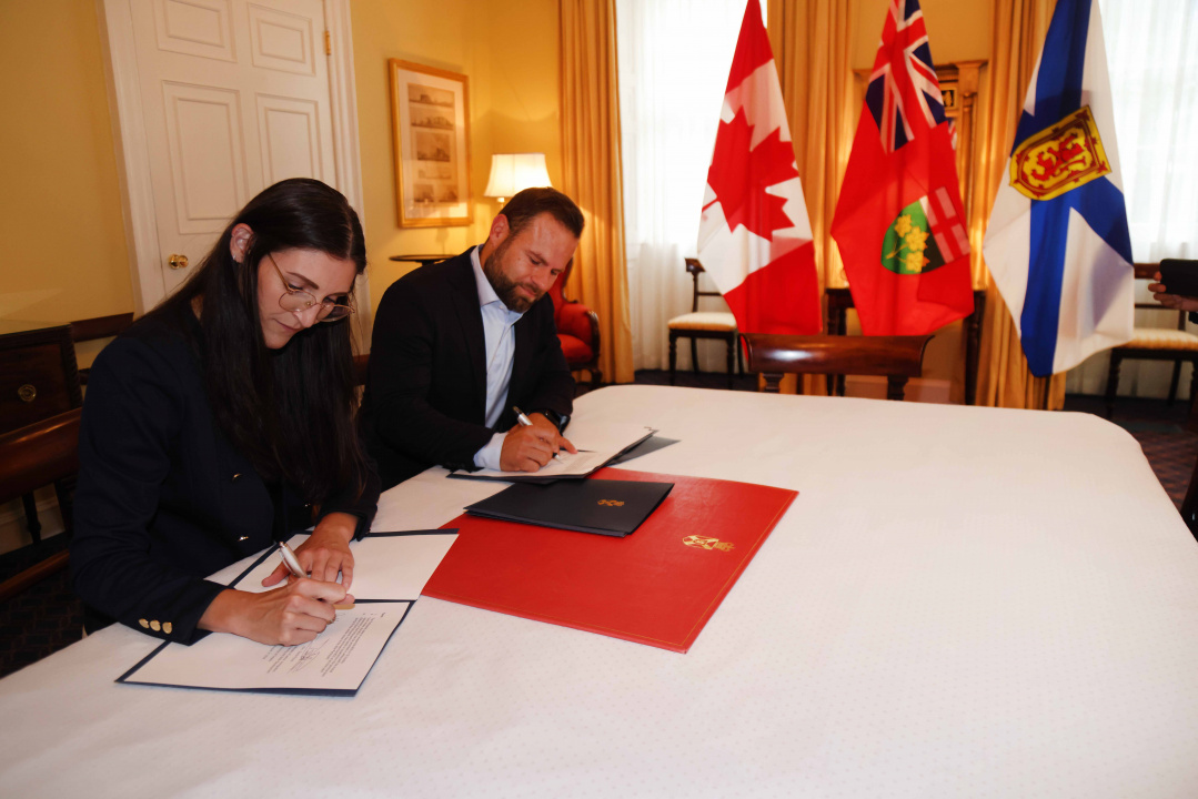 Jill Balser, Minister of Labour, Skills and Immigration, and David Piccini, Minister of Labour, Immigration, Training and Skills Development for the Province of Ontario, sign a memorandum of understanding detailing collaboration between the two provinces to improve recognition of international credentials for skilled trades professionals. 