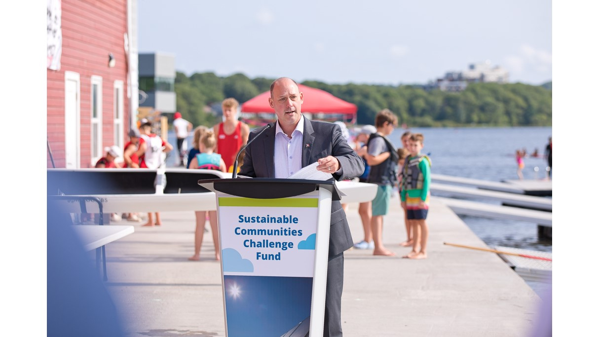 Minister Halman speaks at a podium beside Lake Banook.