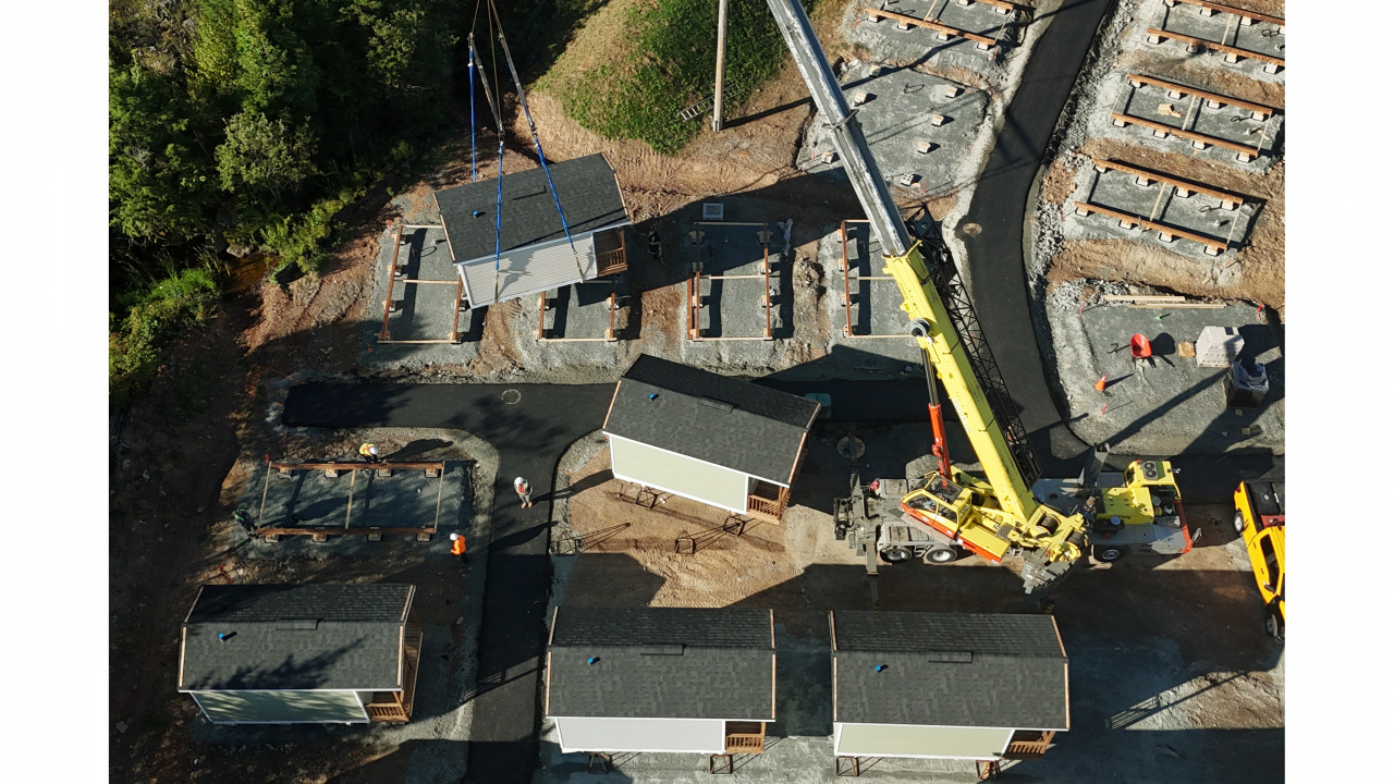 Photo of a crane lowering a tiny home