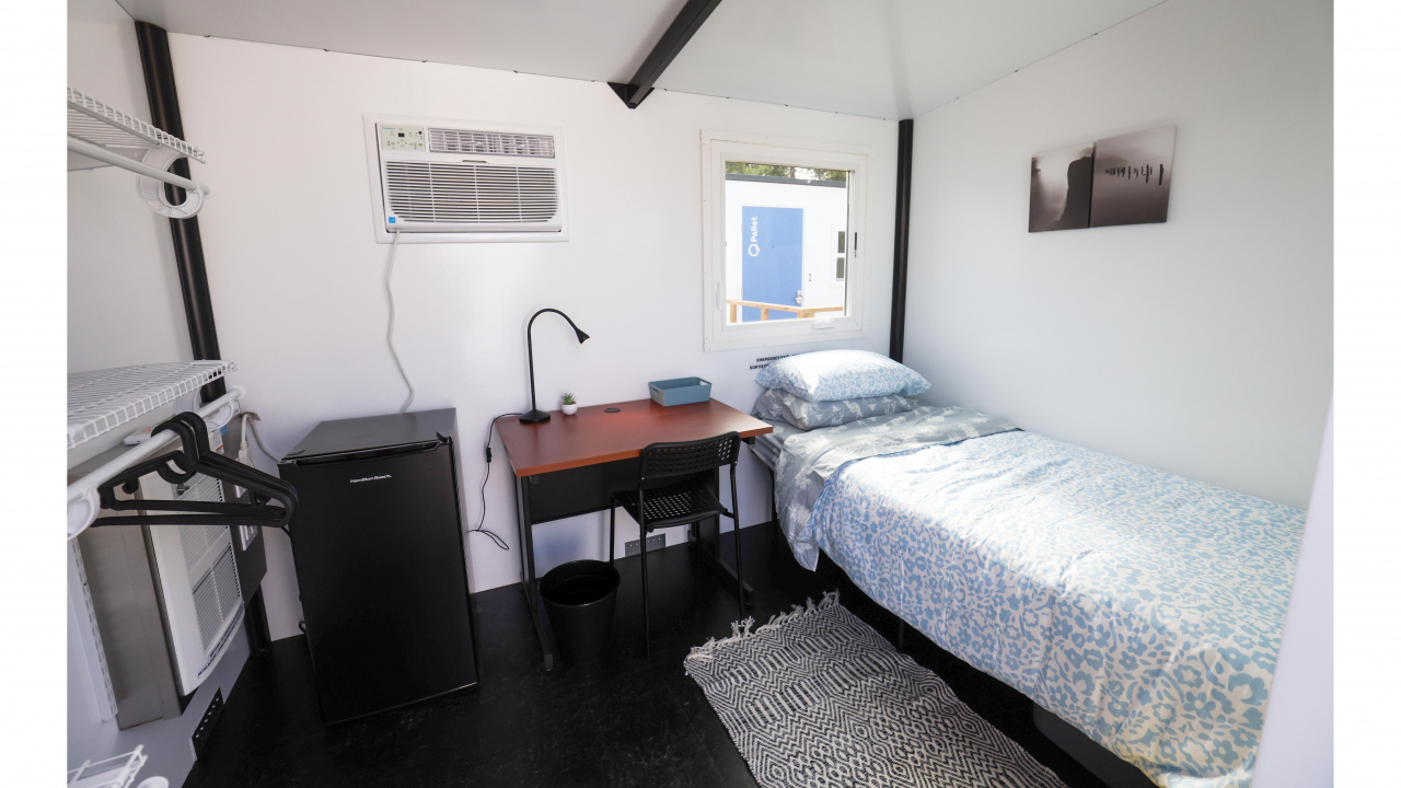 Photo of interior of Pallet shelter with bed, mini fridge and table