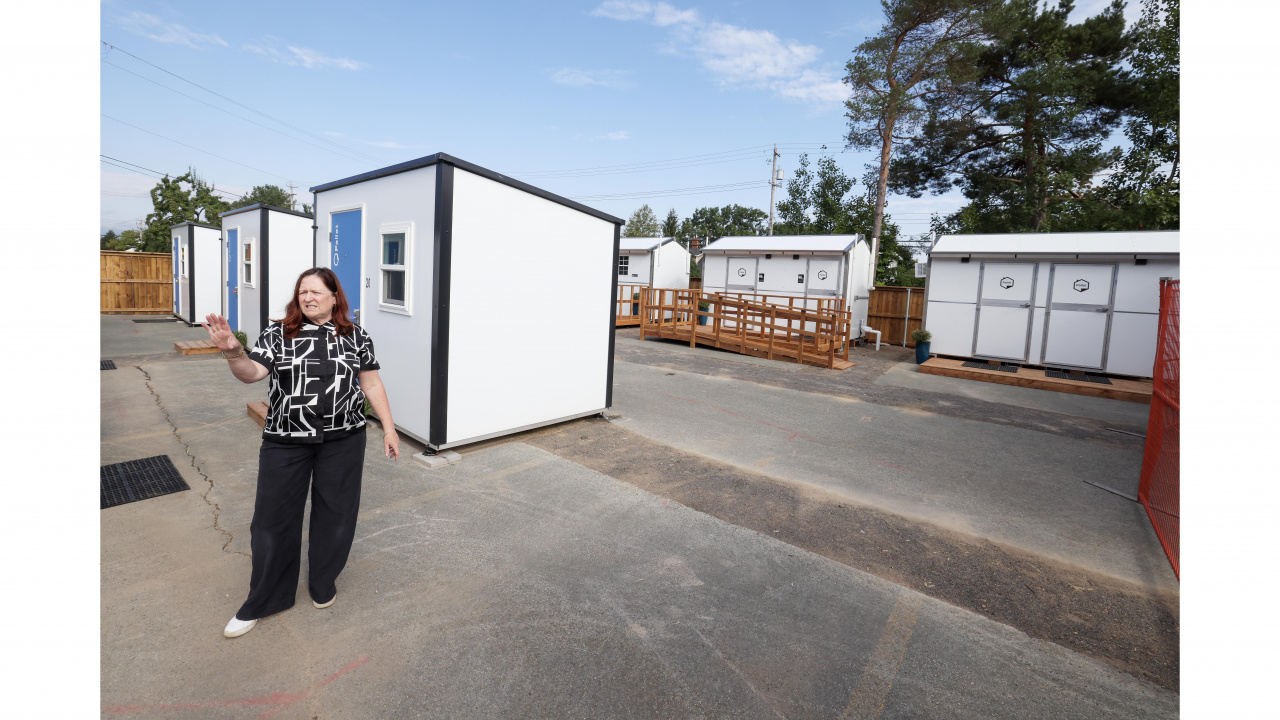 Photo of woman standing outside a Pallet shelter