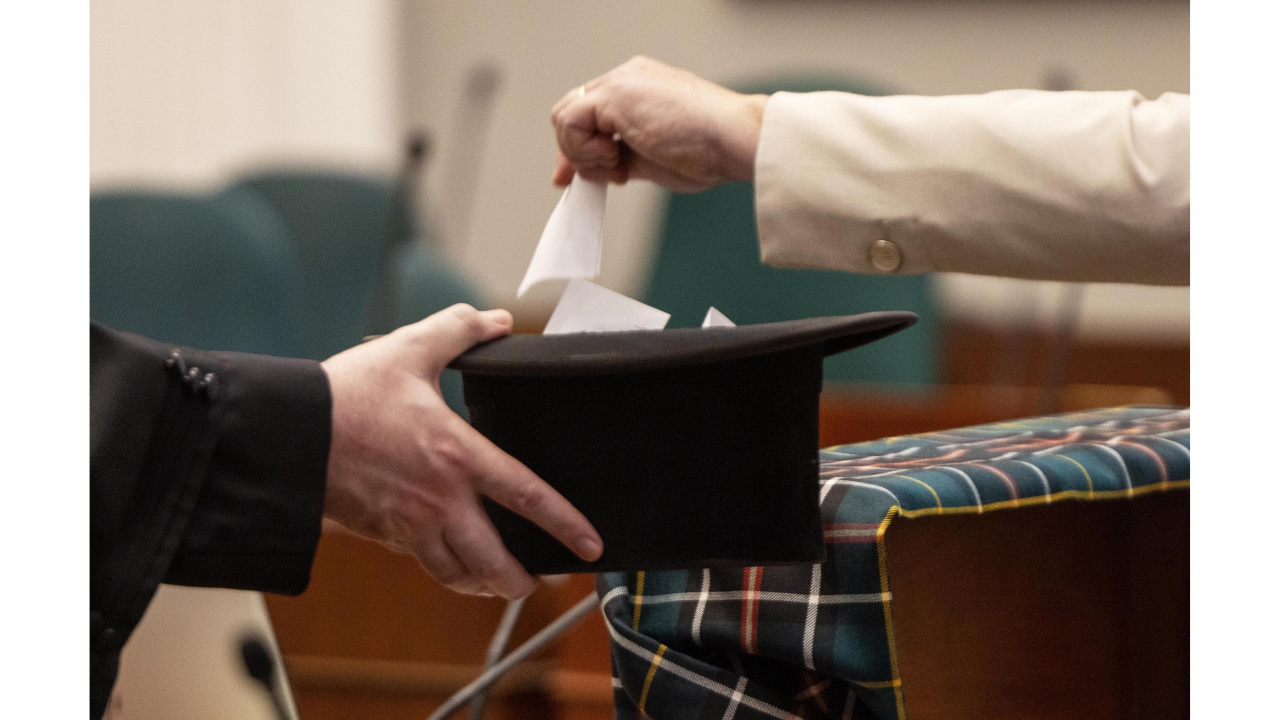 Photo of someone dropping a ballot in a hat