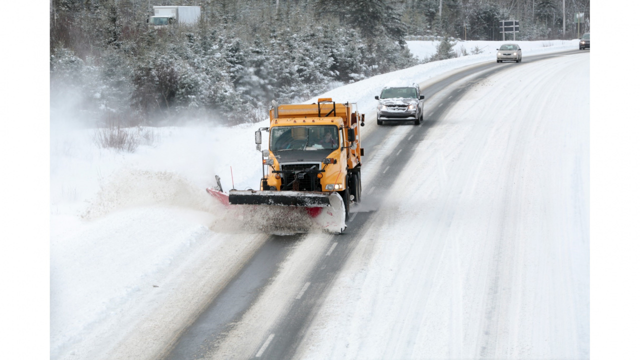 A yellow snowplow truck clears the road.