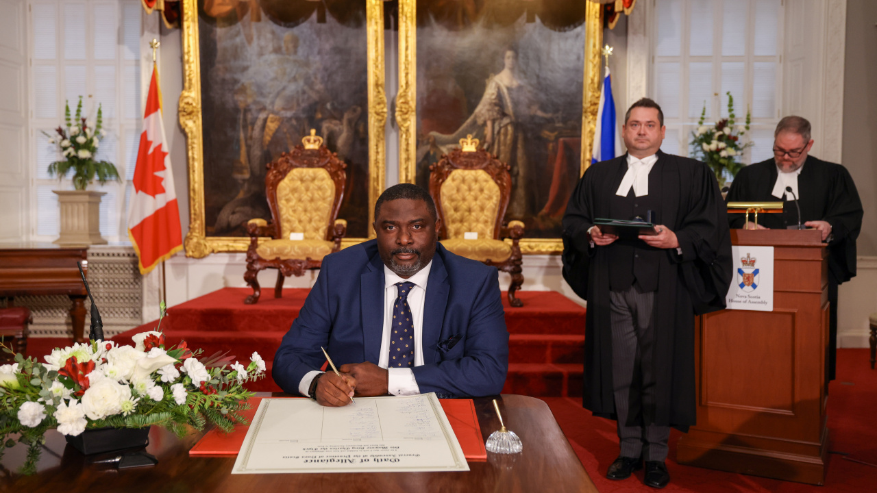 Photo of MLA Adegoke Fadare signing the Oath of Allegiance in the Red Chamber at Province House.