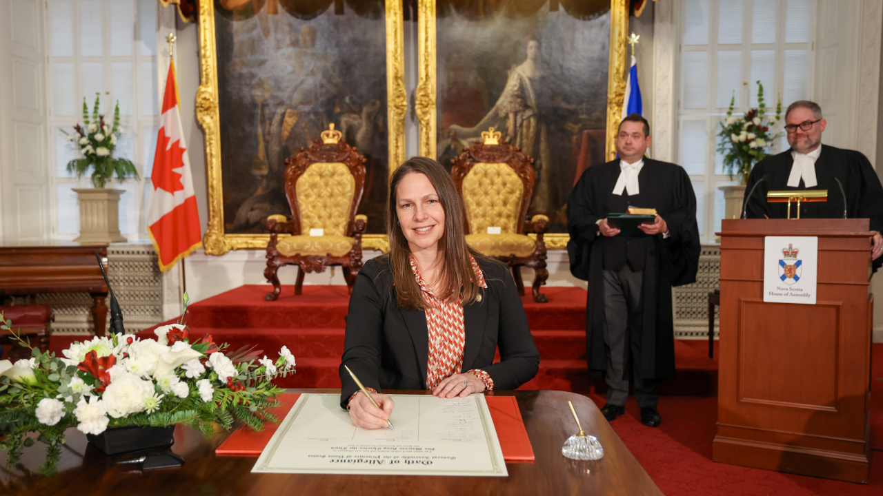 Photo of MLA Becky Druhan signing the Oath of Allegiance in the Red Chamber at Province House.