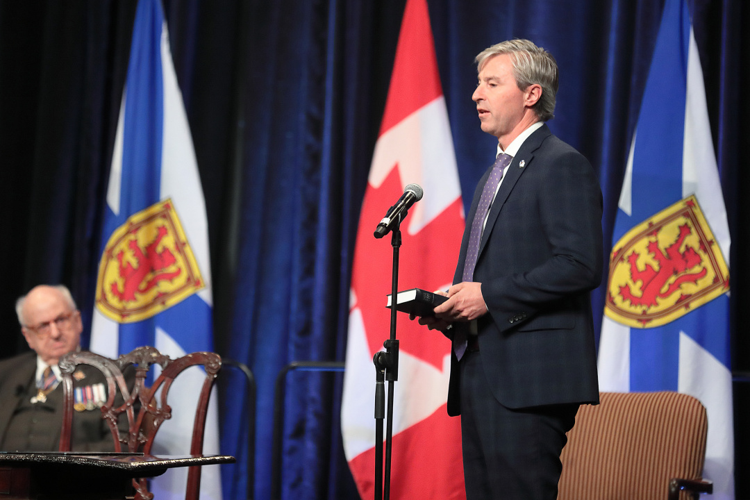 Premier Tim Houston takes the oath of office while Lieutenant Governor Arthur LeBlanc looks on.