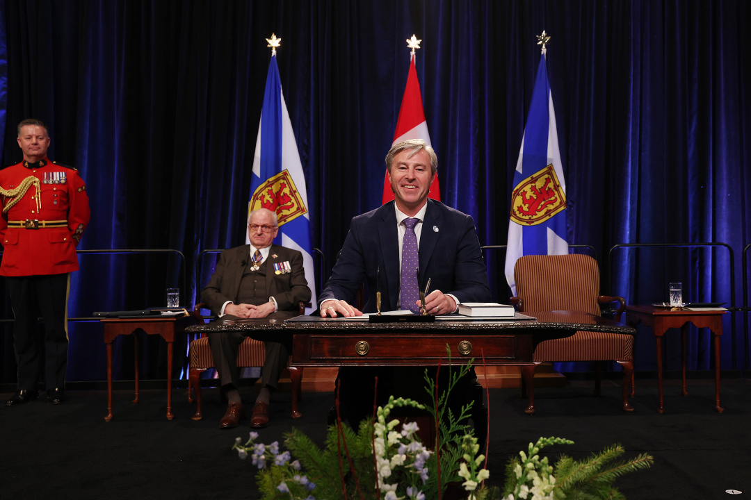 Photo of Premier Tim Houston signing oath of office document