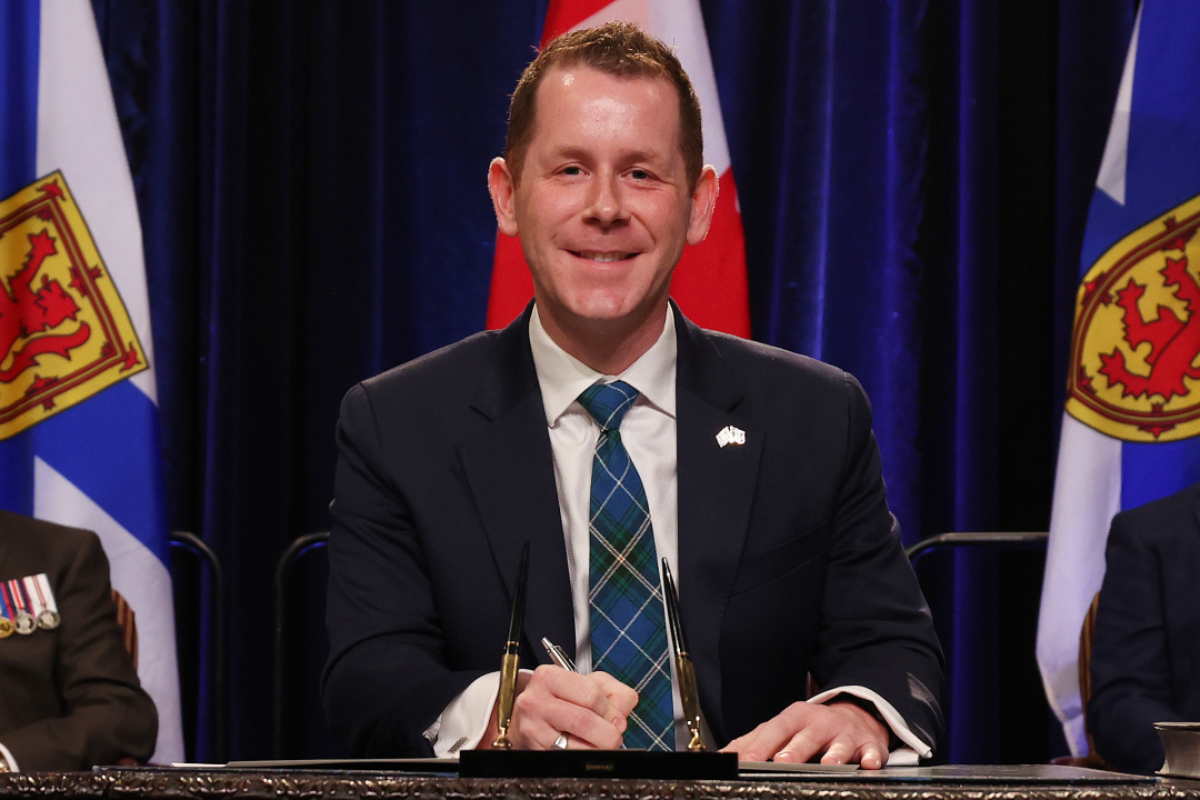 Photo of Minister Colton LeBlanc signing the oath of office document