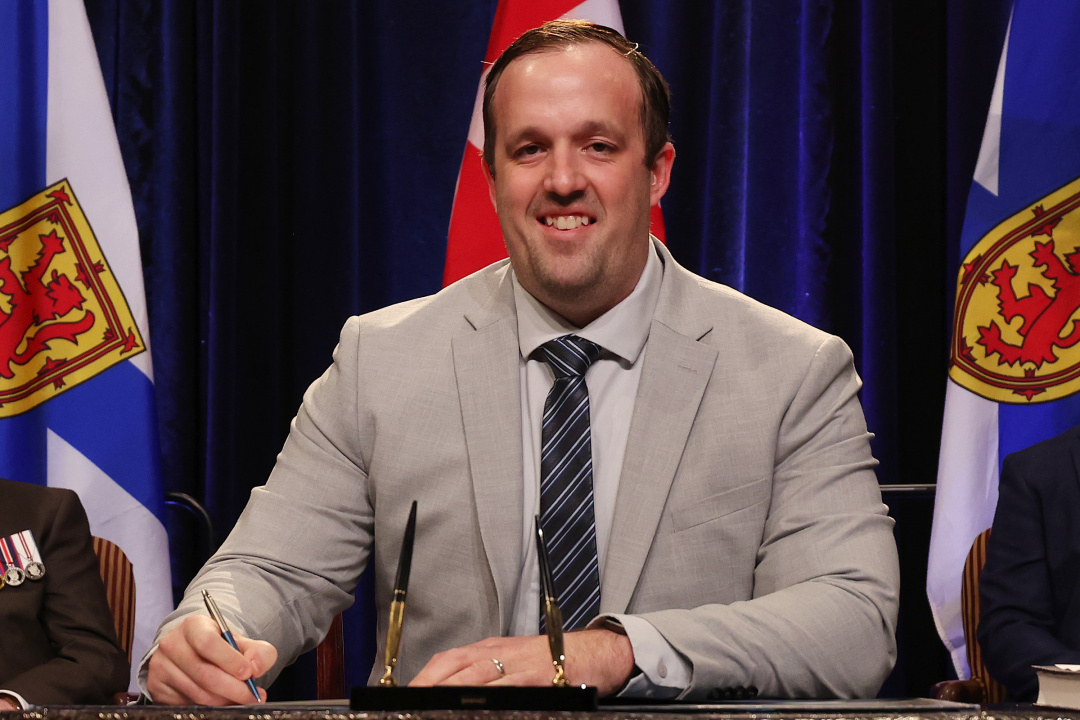 Photo of Minister Brian Comer signing the oath of office document