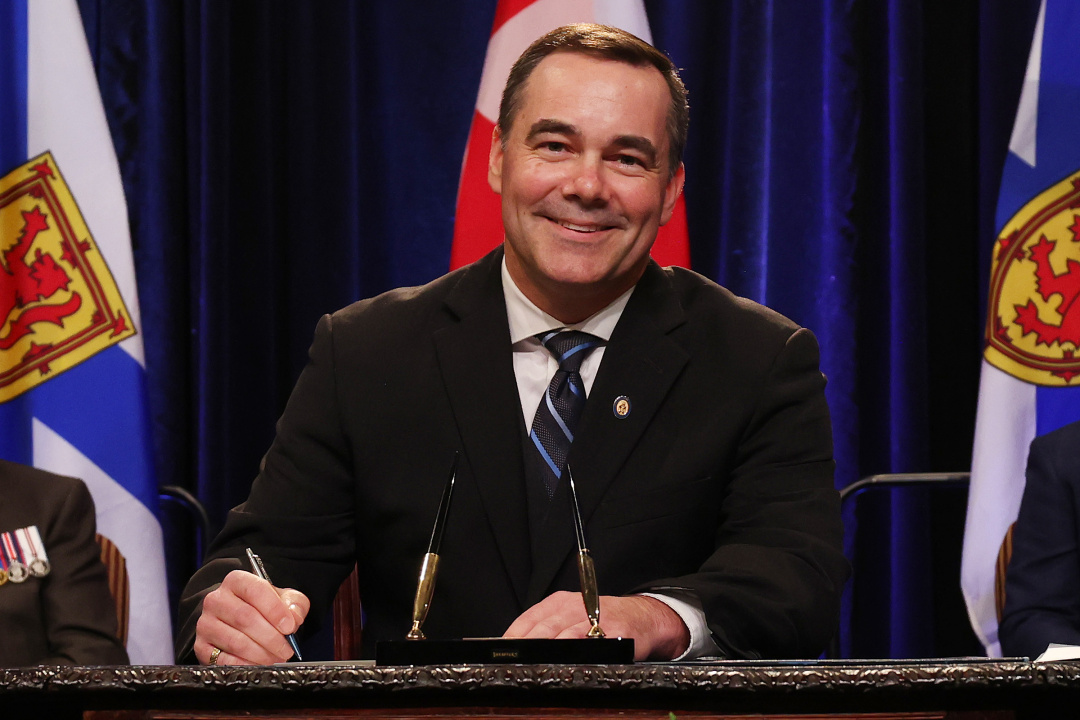 Photo of Minister Kent Smith signing the oath of office document