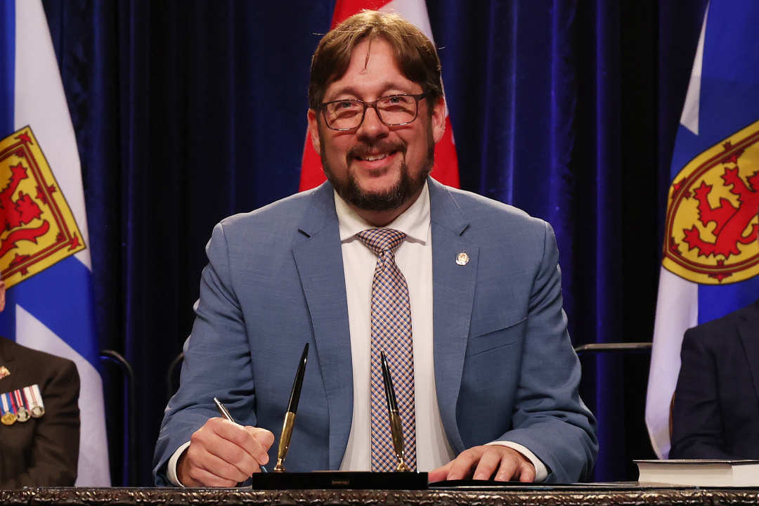 Photo of Minister Trevor Boudreau signing the oath of office document