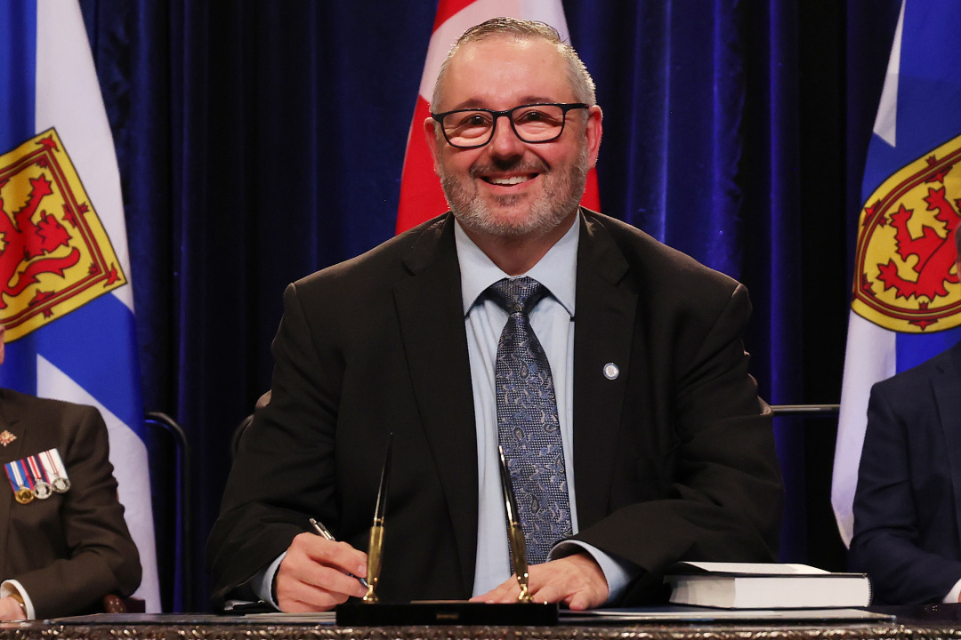 Photo of Minister Fred Tilley signing the oath of office document