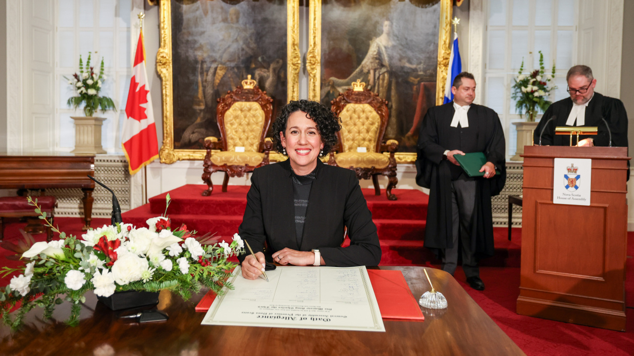 Photo of MLA Claudia Chender signing the Oath of Allegiance in the Red Chamber at Province House.