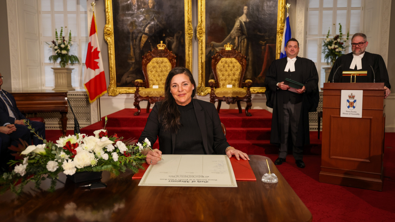 Photo of MLA Danielle Barkhouse signing the Oath of Allegiance in the Red Chamber at Province House.