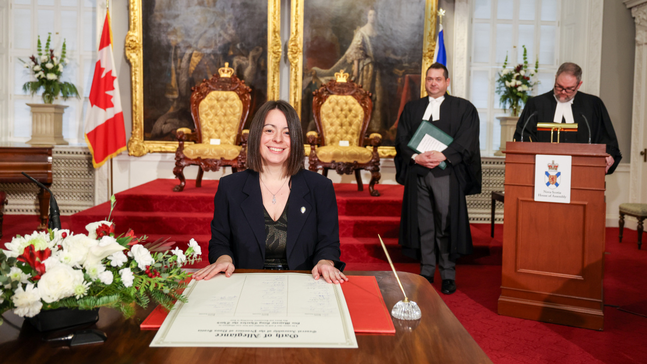 Photo of MLA Kendra Coombes signing the Oath of Allegiance in the Red Chamber at Province House.