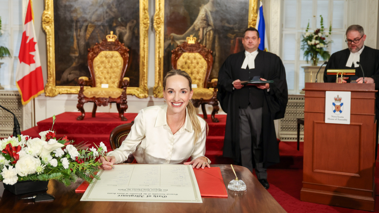 Photo of MLA Krista Gallagher signing the Oath of Allegiance in the Red Chamber at Province House.