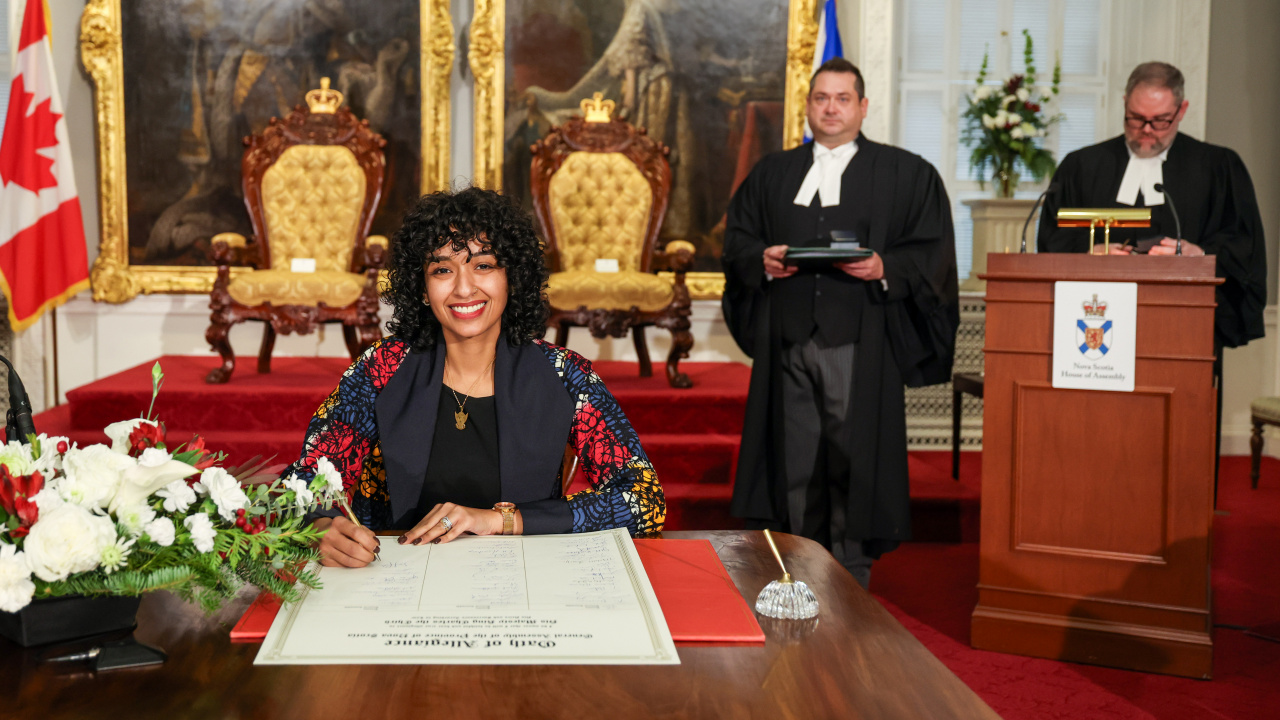 Photo of MLA Lina Hamid signing the Oath of Allegiance in the Red Chamber at Province House.