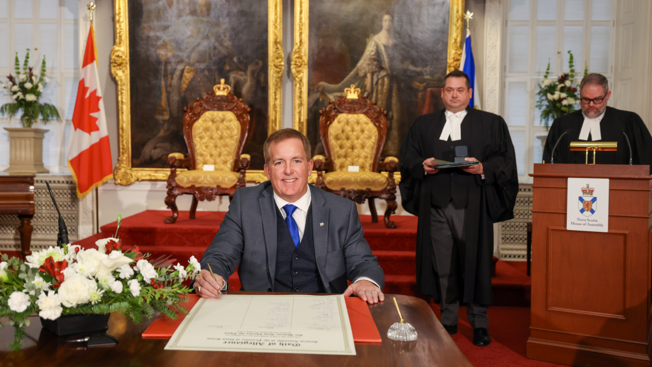 Photo of MLA Scott Armstrong signing the Oath of Allegiance in the Red Chamber at Province House.