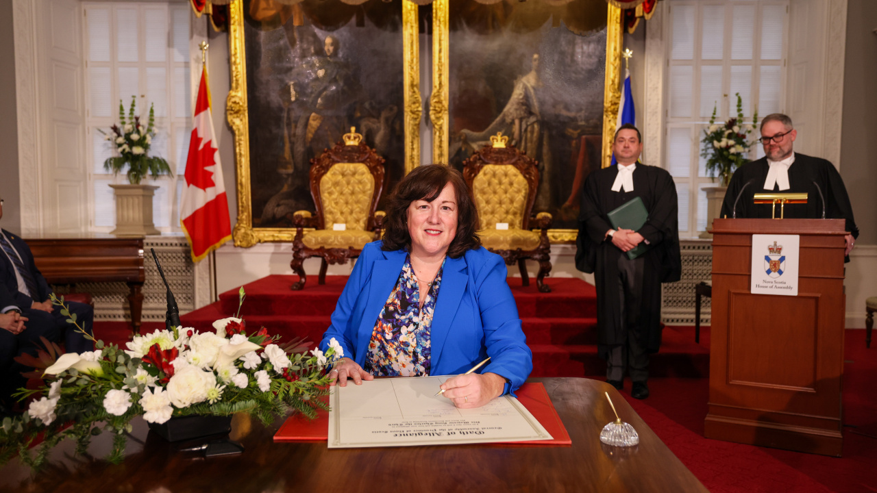 Photo of MLA Susan Corkum-Greek signing the Oath of Allegiance in the Red Chamber at Province House.