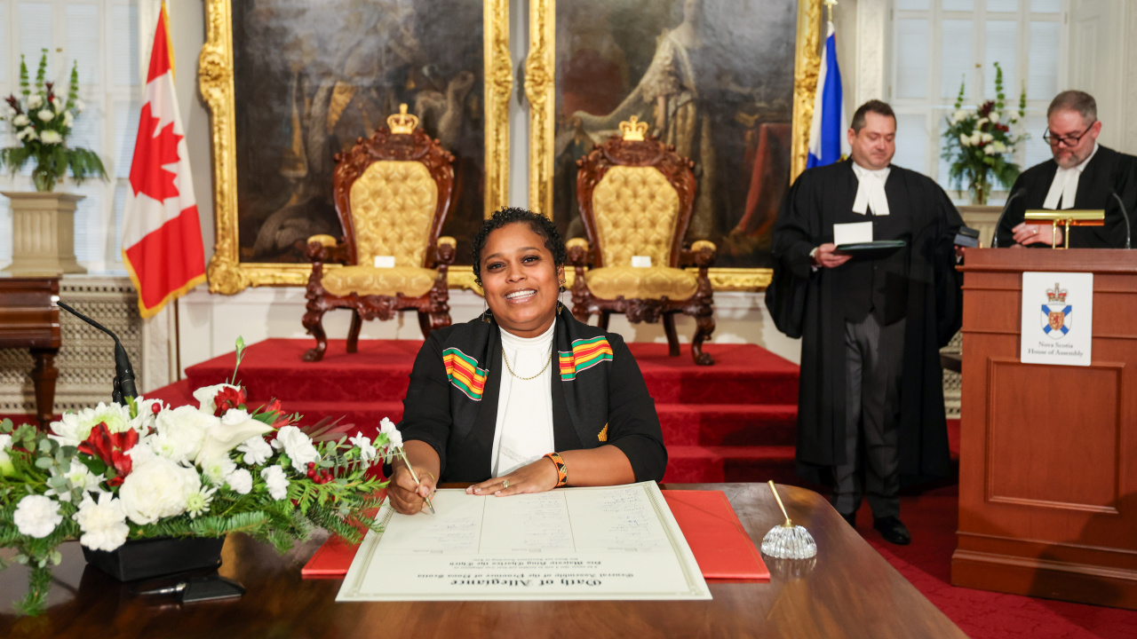 Photo of MLA Suzy Hansen signing the Oath of Allegiance in the Red Chamber at Province House.