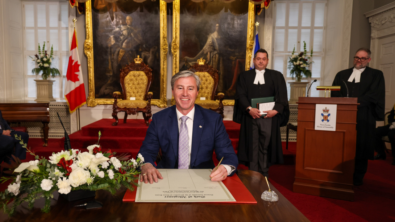 Photo of MLA Tim Houston signing the Oath of Allegiance in the Red Chamber at Province House.