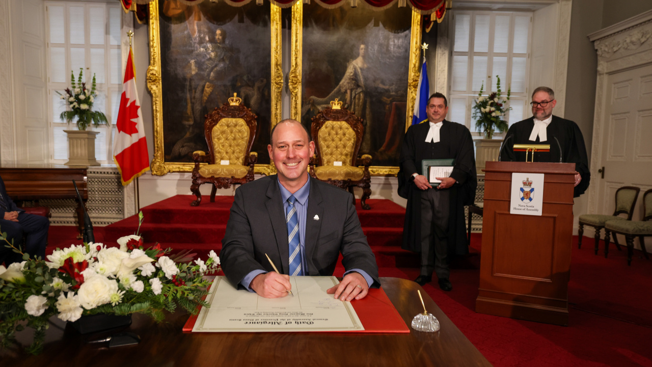 Photo of MLA Timothy Halman signing the Oath of Allegiance in the Red Chamber at Province House.