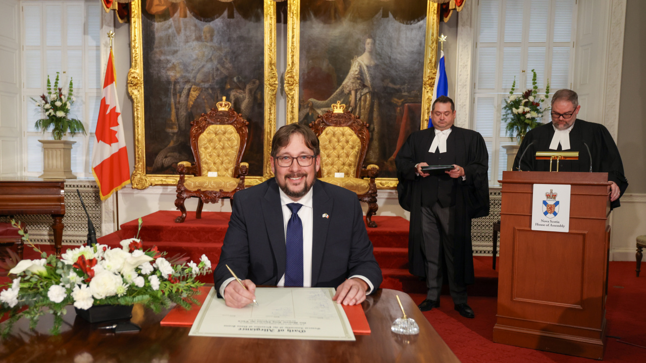 Photo of MLA Trevor Boudreau signing the Oath of Allegiance in the Red Chamber at Province House.