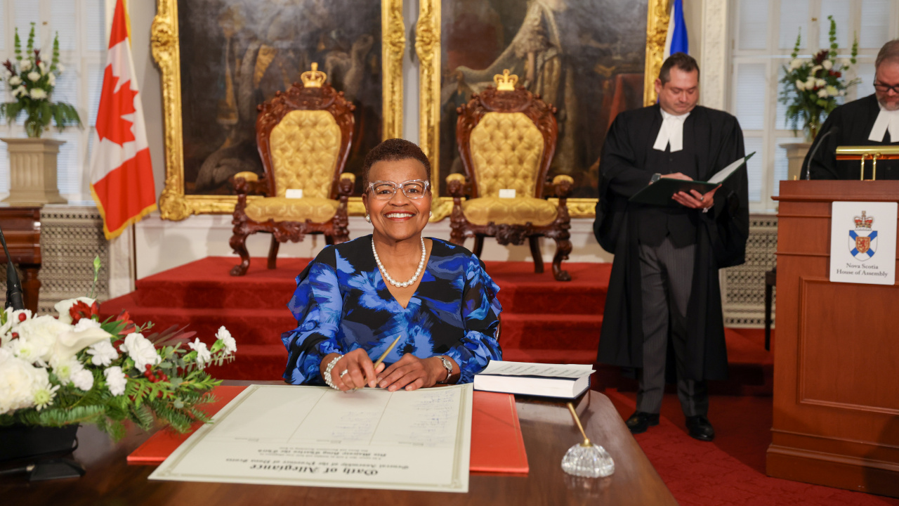 Photo of MLA Twila Grosse signing the Oath of Allegiance in the Red Chamber at Province House.