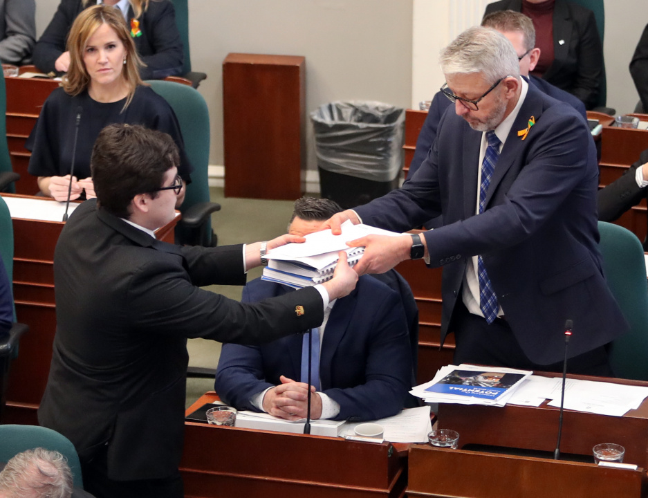 Finance and Treasury Board Minister John Lohr passes dcouments to a page in the legislative chamber