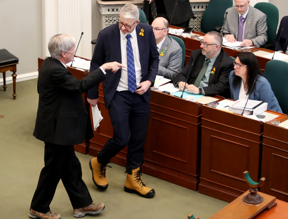 Finance and Treasury Board Minister John Lohr walks in the legislative chamber wearing work boots