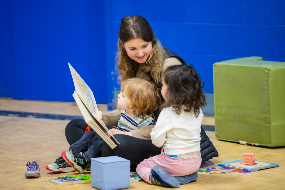 Early childhood educator reading to two children