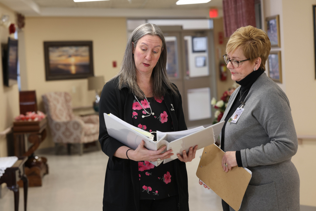 Allana Bowles, registered nurse prescriber (left), reviews care information with The Cove Guest Home Administrator Cheryl Deveaux. 