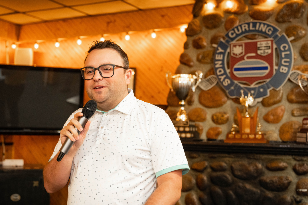 Travis Stone, president of the Sydney Curling Club, speaking into a microphone