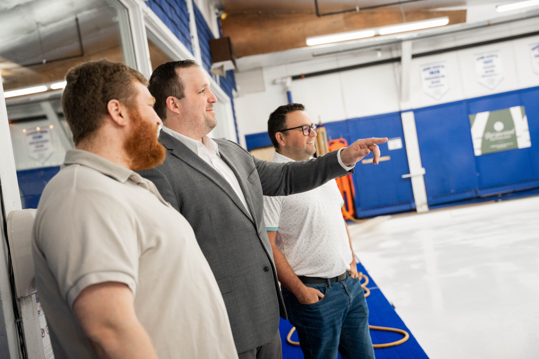 Todd Mercer, vice president of the Sydney Curling Club, Minister Brian Comer and new club president Travis Stone look over a curling ice surface