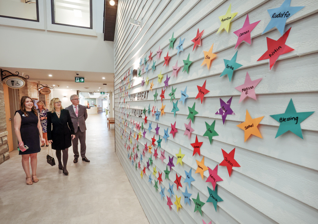 L-R: Moody Hall General Manager Emily Dewar; Seniors and Long-Term Care Minister Barbara Adams; and Damian Stoilov, Bedford South MLA, look at a wall of stars featuring the names of Moody Hall staff members.