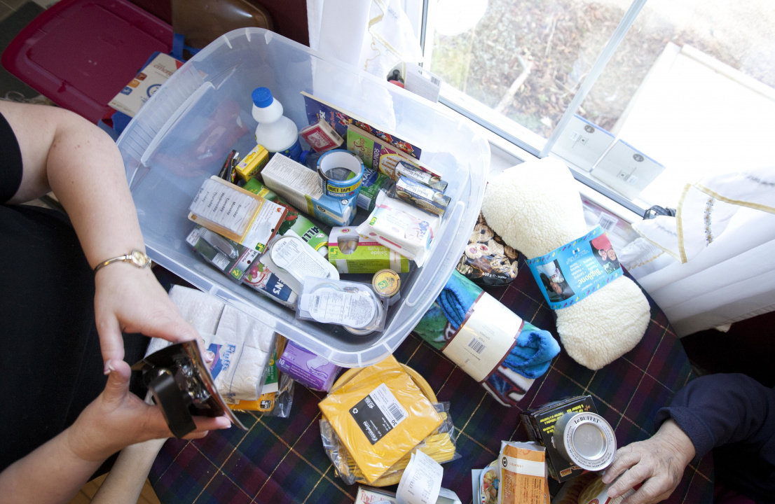 Emergency kit supplies in a plastic bin and on a table / Articles pour une trousse d'urgence dans un bac de plastique, sur une table