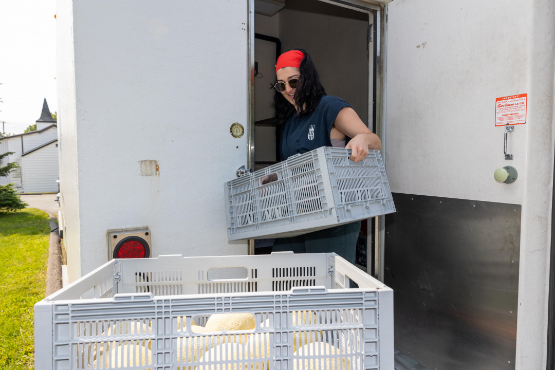 Une personne remplit un camion réfrigéré de fruits et de légumes.